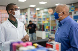 Pharmacist and patient talking with masks on
