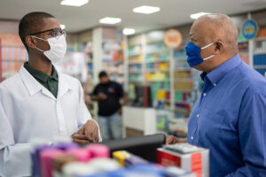 Pharmacist and patient talking with masks on