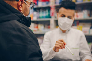 Pharmacist and patient talking while wearing masks